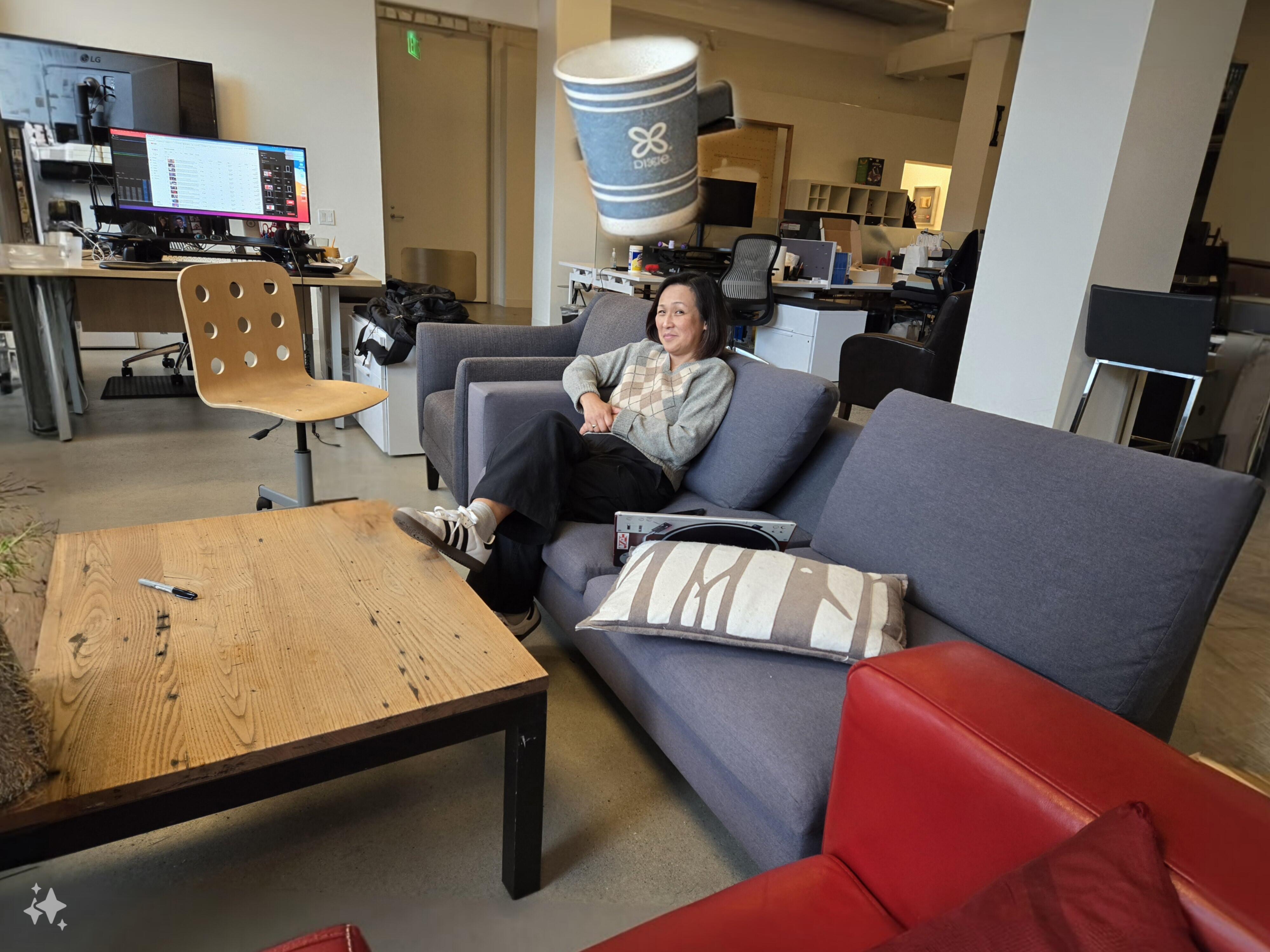 A woman sitting on a couch with a giant coffee cup floating above